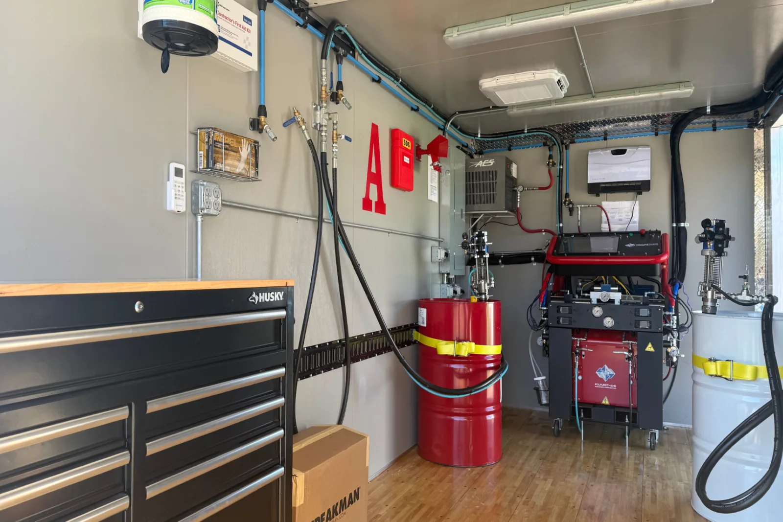Interior of a Profoam spray rig: proportioner, heated hose reels and A/B material drums. Representative Profoam equipment, not a photograph of Patriot's own rig.